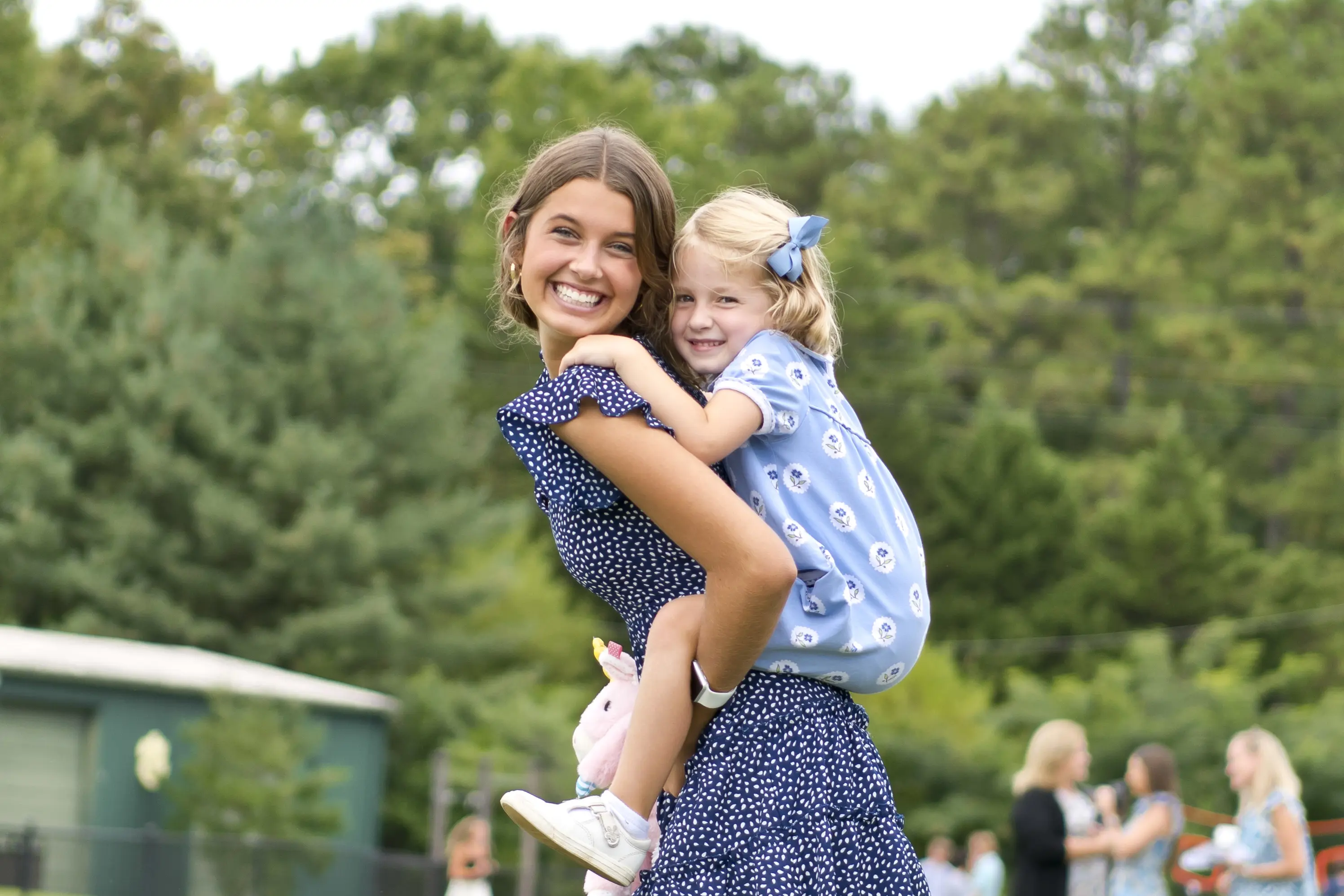 Upper School student giving a Lower School student a piggyback ride.