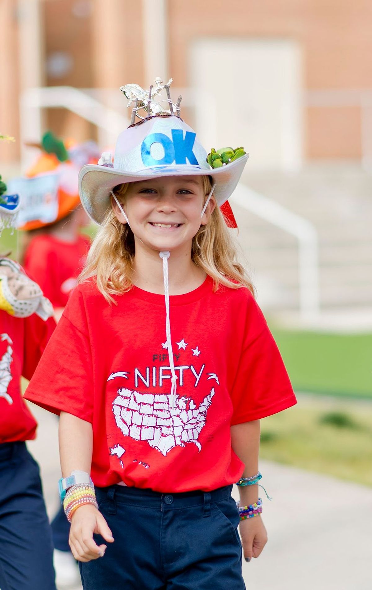 Students walking on the parade wearing a state hat