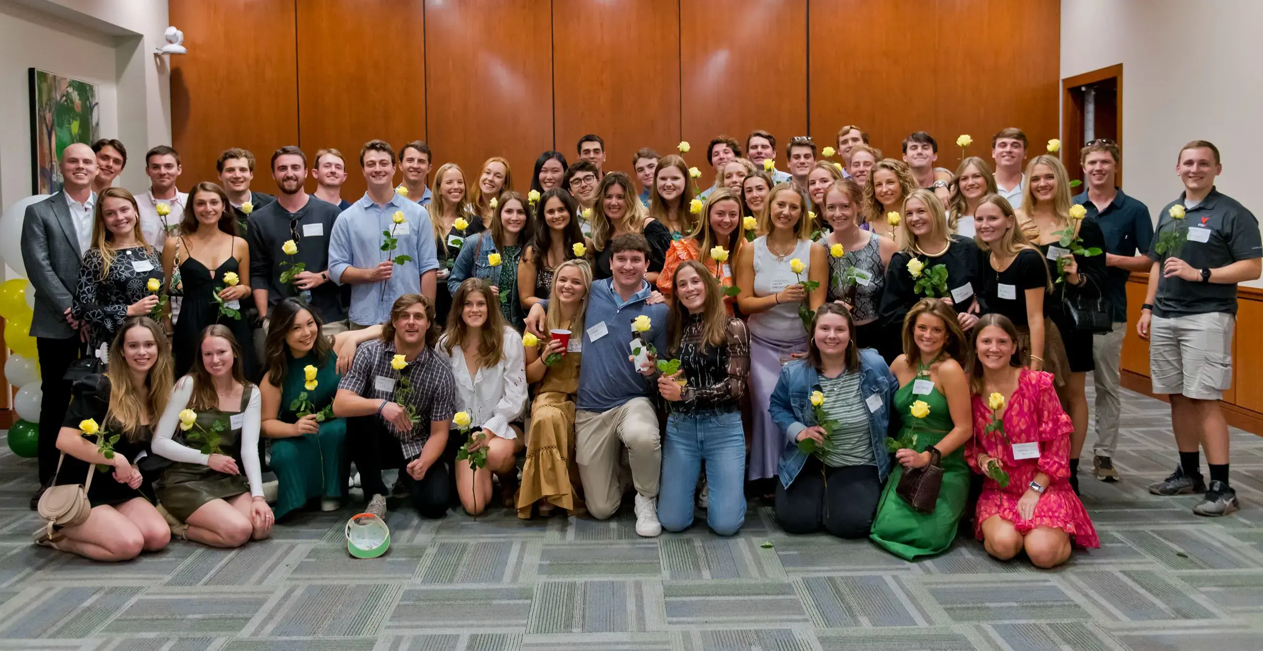 Group photo of the alumni at a event holding a yellow flower