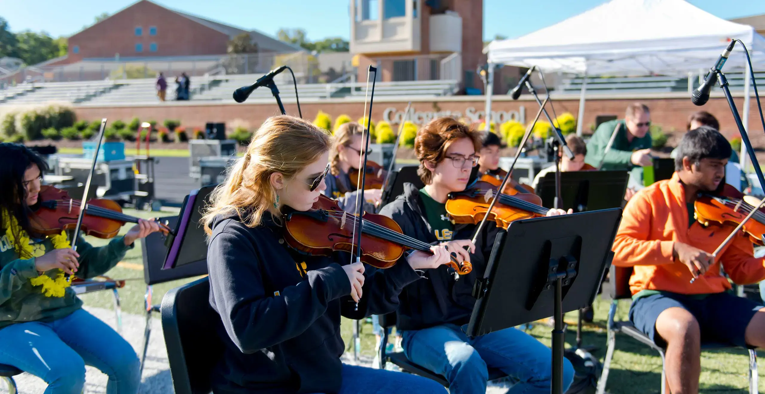 Group of Collegiate students playing violin outdoors