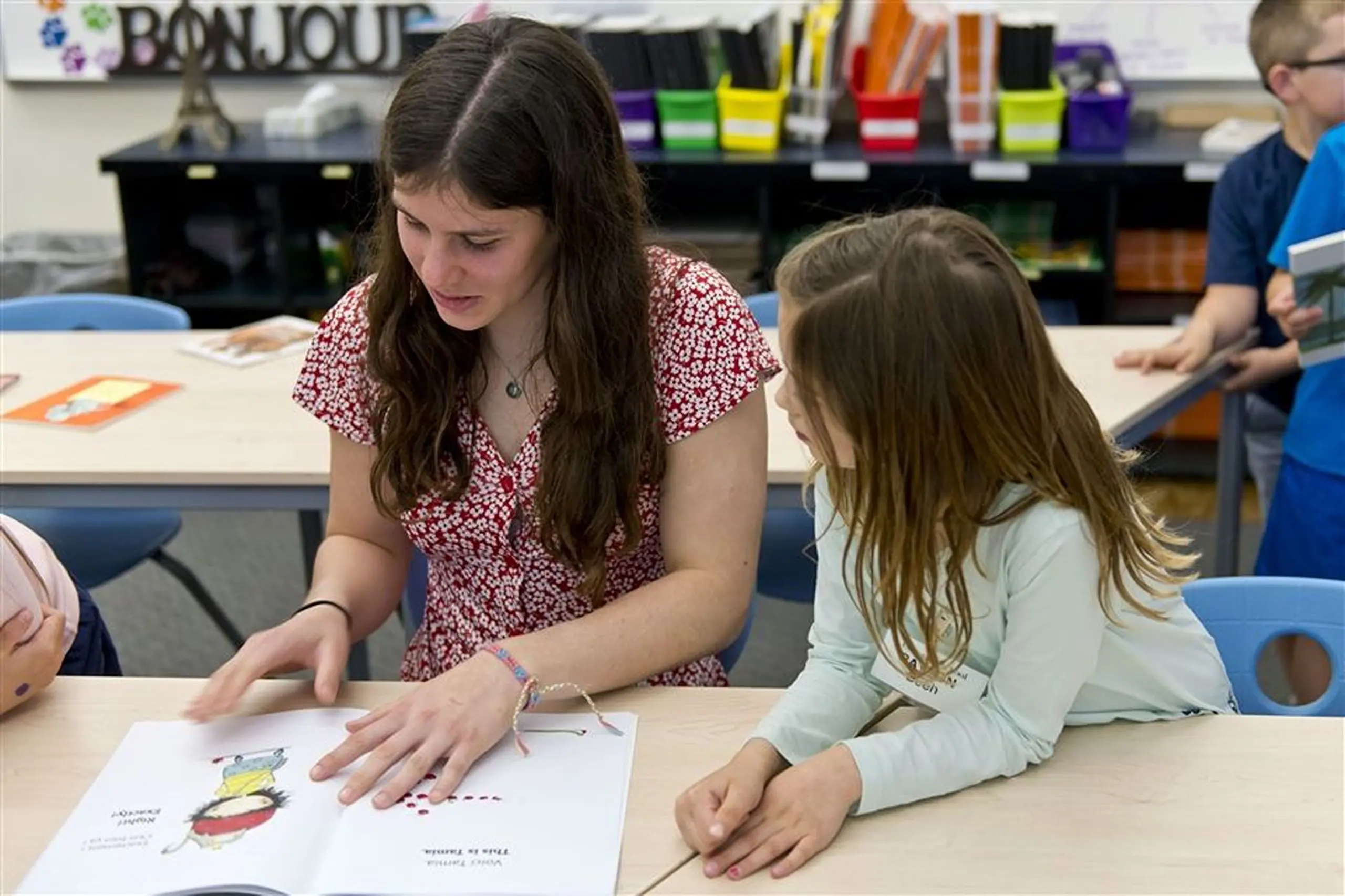 middle school student reading with lower school student