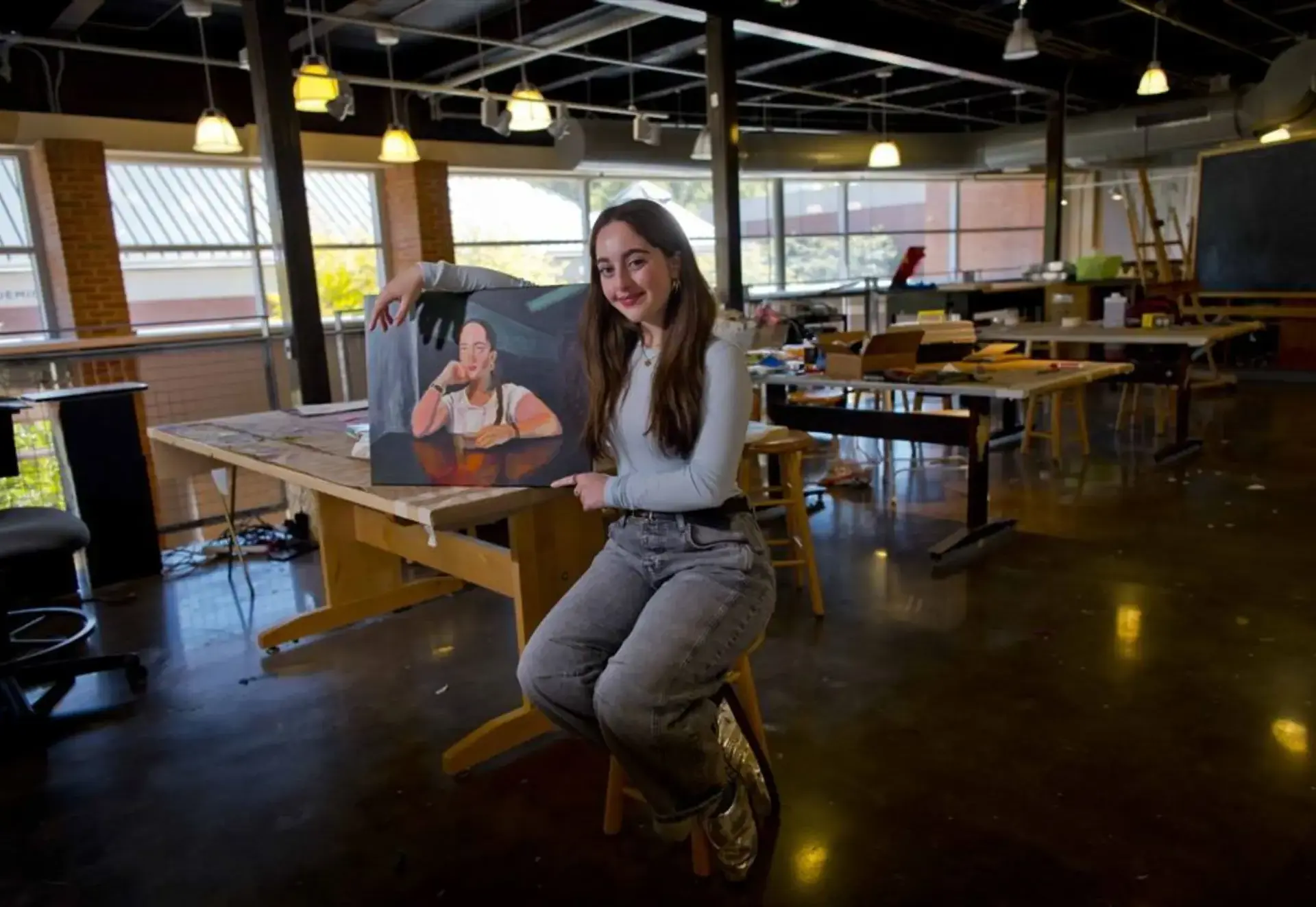 Rachel sitting next to her painting